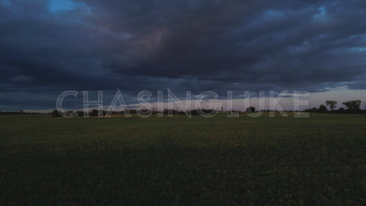 Low Fast Aerial Over Farm Field With Dark Clouds Above