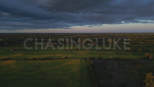 Slow High Aerial Over Farm Field at Golden Hour With Dark Clouds Approaching